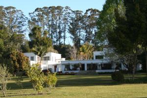 a large white house with trees in the background at Edenbrook Country Manor in Plettenberg Bay