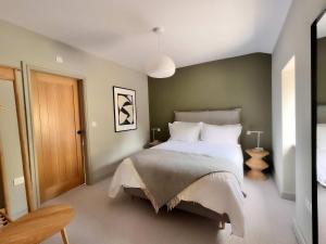 ein Schlafzimmer mit einem großen Bett und weißen Kissen in der Unterkunft A Beautiful 3 Bedroom 17th Century Stone cottage in Llanddyfnan