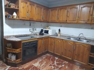 a kitchen with wooden cabinets and a sink and a microwave at Casa Frasco in Luque