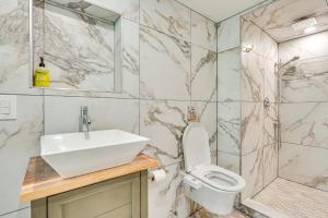 a bathroom with a sink and a toilet and a shower at Walk to Waterfront Chic Hudson Valley Garden Apt in Kingston +16 photos