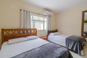 a bedroom with two beds and a window at Casa com piscina e churrasqueira na Praia Seca in Araruama +38 photos