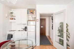 une cuisine avec des armoires blanches et une table en verre dans l'établissement Central and Hip w King Bed, 50m tram and bus, Netflix, à Helsinki