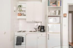 une cuisine avec des armoires blanches et un réfrigérateur blanc dans l'établissement Central and Hip w King Bed, 50m tram and bus, Netflix, à Helsinki 6 autres photos