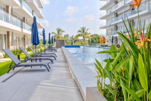 a row of chaise lounge chairs next to a swimming pool at Quinta San Miguel Ocean & Canal in Nuevo Vallarta