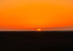 a sunset on the beach with the sun in the horizon at Casa Solayla Origomare in Lajares