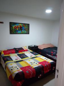 a bedroom with a bed with a colorful quilt on it at Continental Aparta Hotel Duitama in Duitama