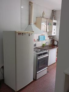 Una cocina con estufa y refrigerador blanco. en Sarratea 1427, en Santiago del Estero 3 fotos más