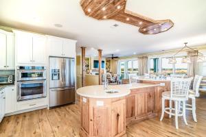 una cocina con armarios blancos y una isla de cocina con sillas en Paradise Point: Luxury Beachfront Home with Views, en Pawleys Island