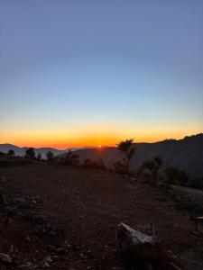 a sunset on a hill with the sun setting at The Tatwa Hotel & Camping in Chakrāta +1 photo