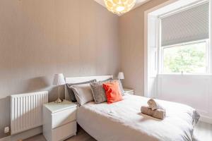 a bedroom with a white bed with orange pillows and a window at Spacious 3 bed home in Marchmont in Edinburgh