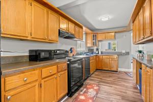a kitchen with wooden cabinets and black appliances at Cozy 3 Bedroom Near Airport And Downtown Detroit in Dearborn Heights