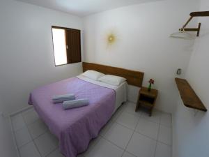 a bedroom with a purple bed with two towels on it at Flat Vila dos Milagres in São Miguel dos Milagres +11 photos