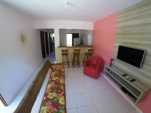 a living room with a tv and a red chair at Flat Vila dos Milagres in São Miguel dos Milagres
