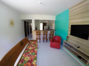 a living room with a television and a red chair at Flat Vila dos Milagres in São Miguel dos Milagres
