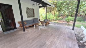 a porch of a house with a couch and a table at Four Monkeys Eco Lodge Jungle & Beach - The House in Cabo Matapalo