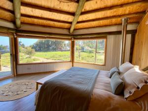 a bedroom with a large bed with a large window at Espectacular Cabaña con acceso a la playa in Puchuncaví
