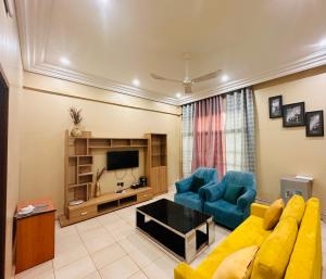 a living room with a yellow couch and blue chairs at Résidence Nana Baco Djicoroni in Bamako