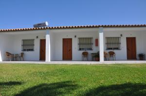 a white house with wooden doors and chairs in a yard at El Levante in Tarifa