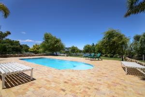 a swimming pool with two benches in a park at Skilpadvlei Wine Farm in Stellenbosch
