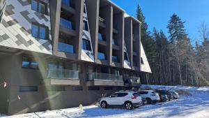 a parking lot with cars parked in front of a building at Green peace-Bjelašnica in SJJ