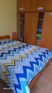 ein Bett mit einer blau-weißen Bettdecke darauf in der Unterkunft DEPTO en SANTA TERESITA PARA 4 PERSONAS- EXCELENTE UBICACIÓN- NO se aceptan mascotas- 5 cuadras Playa - 2 Bingo y cerca centro y Bosque - CONSULTAR DISPONIBILIDAD POR CELULAR in Santa Teresita