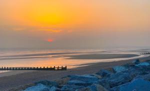 a sunset over a beach with a pier and the ocean at MP303 Parkdean Camber Sands in Camber