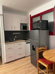 a kitchen with a table and a stainless steel refrigerator at Jolie T2 en plein centre-ville ville de Font-Romeu in Font Romeu Odeillo Via
