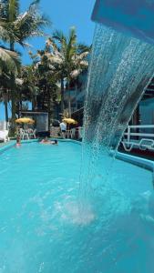a fountain in a swimming pool with people in the water at Pousada Bella Praia in Torres