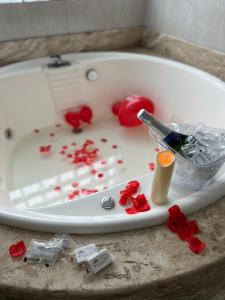 a white bath tub filled with red flowers and a knife at Pousada Bella Praia in Torres