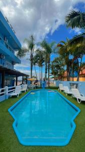 a large swimming pool with chairs and palm trees at Pousada Bella Praia in Torres