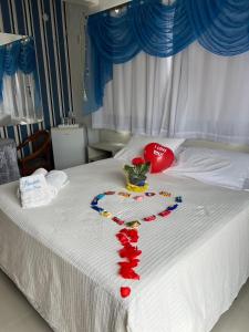 a white bed with red hearts and a vase on it at Pousada Bella Praia in Torres