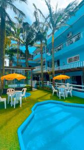 a resort with a swimming pool and tables and umbrellas at Pousada Bella Praia in Torres