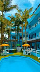 a pool with tables and umbrellas in front of a building at Pousada Bella Praia in Torres