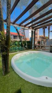 a hot tub in a yard with a palm tree at Pousada Bella Praia in Torres