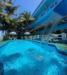 a swimming pool with a fountain in the middle at Pousada Bella Praia in Torres