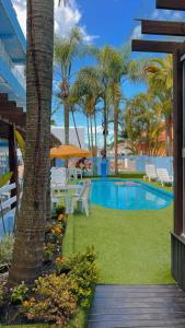 a swimming pool with tables and chairs and palm trees at Pousada Bella Praia in Torres