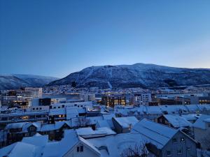 een stad bedekt met sneeuw met bergen op de achtergrond bij Apartment in Tromsø City Centre in Tromsø +14 foto's
