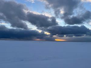 a cloudy sky over the ocean with the sun setting at Kambur Cottages in Snæfellsbær