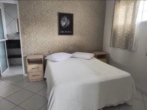 a bedroom with a white bed and a picture on the wall at Pousada Bella Praia in Torres