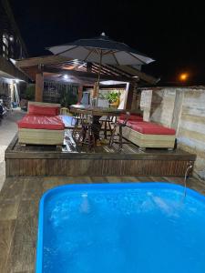 a swimming pool with a table and chairs and an umbrella at Recanto CostaCastilho in Bertioga +18 photos