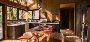 a kitchen with a table and a sink and some windows at Refugios Australes en Corralco in Malalcahuello