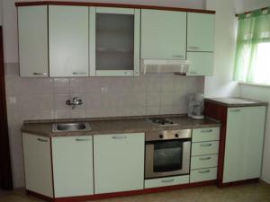 uma cozinha com armários brancos e um lavatório em Villa Maja original since 2005 em Baska Voda