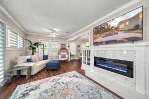 een woonkamer met een grote flatscreen-tv boven een open haard bij Step into the charm of yesteryear with the modern comforts of today at City Cottage! in Sarasota