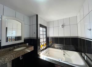 a bathroom with a tub and a sink and a mirror at Pousada Bella Praia in Torres