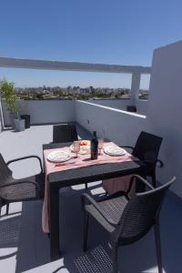 ein Tisch und Stühle auf einem Balkon mit Essen darauf in der Unterkunft LEVEL Terrazas premium con parrillas privadas in Bahía Blanca
