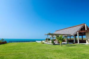 a house with a grassy yard with the ocean in the background at Lyttos Bungalows in Icapuí