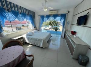 a bedroom with a bed and two windows and a table at Pousada Bella Praia in Torres