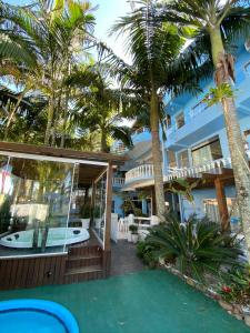 a house with palm trees and a swimming pool at Pousada Bella Praia in Torres