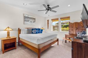 a bedroom with a bed with a ceiling fan and a desk at Halii Kai 20D in Waikoloa