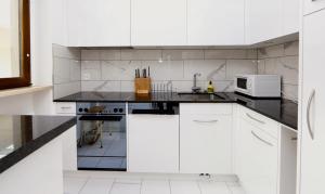 a white kitchen with white cabinets and a microwave at Ferienwohnung D28 in Orselina